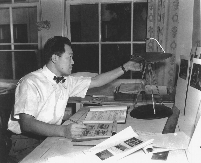 Paramount unit art director Albert Nozaki in 1951, sketching some of the continuity drawings for George Pal's adaptation of The War of the Worlds.  For reference, Nozaki used a copper and Lucite prototype of the Martian war machine constructed by the Paramount prop department from his original drawings.  In this later stage of the machine's evolution, all the essential details of its design have been resolved except for the positioning of the cobra head-shaped heat ray.  The heat ray was finally placed slightly forward of center instead of at the rear as shown in this photograph. Click to enlarge.
