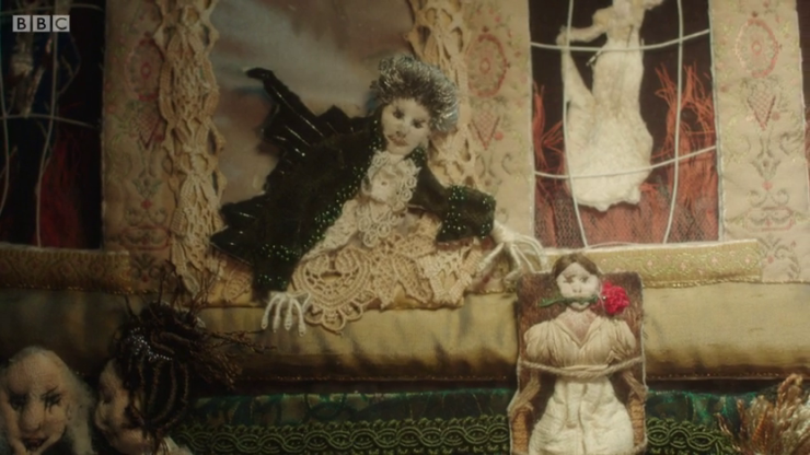 [Image: part of Lady Pole's fabric art from episode 3, showing the two versions of herself and the gentleman looming]