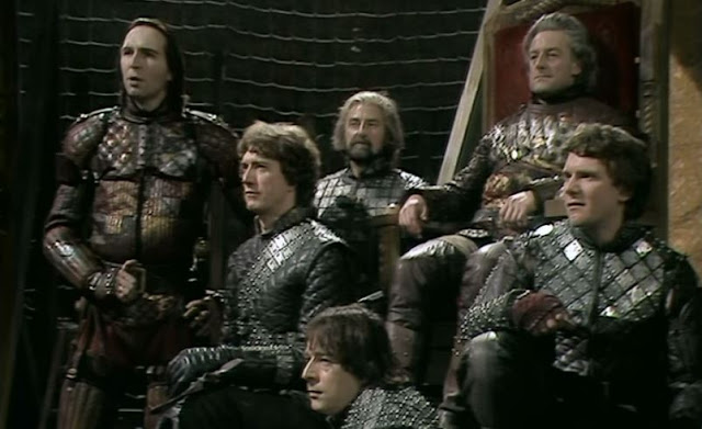 Mark Wing-Davey as the valiant armored Warwick (left) with York (enthroned) and his three sons, from the Jane Howell production, BBC Shakespeare Collection.