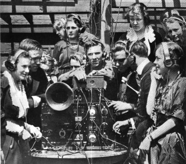 Members of a teen social club listen to an early radio