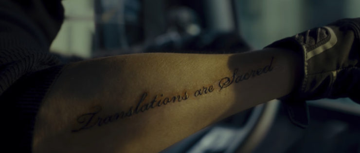 Afreshly tattooed forearm showing raised black script reading “Translations are Sacred.” From the movie Okja.