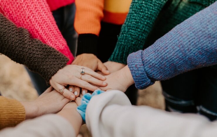 Close-up group positioned in a circle with their hands gathered together in the center