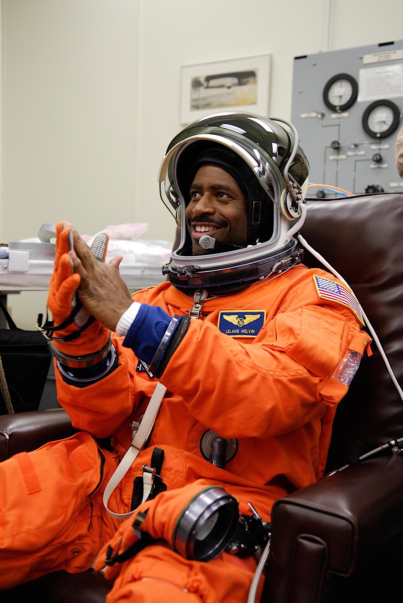 Mission Specialist Leland Melvin tests his gloves for a final fitting before space shuttle Atlantis' launch.