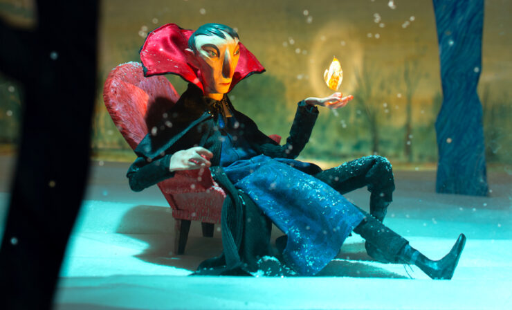 Sculpture of Judge Dee seated in a snowy forest, his left hand raised and holding a flame.