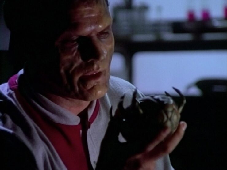 Drake (Marshall Teague) holds an alien device in Babylon 5 "Infection"