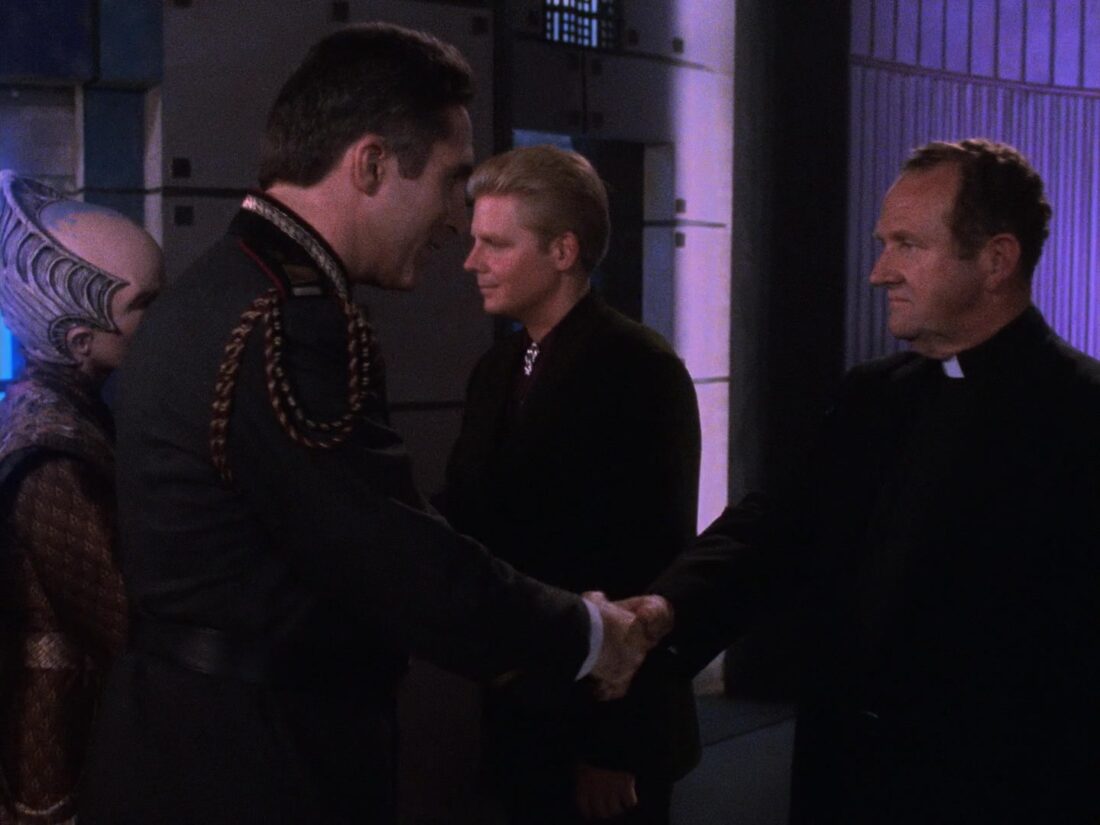 Sinclair shakes hands with a Catholic priest in Babylon 5 "The Parliament of Dreams"