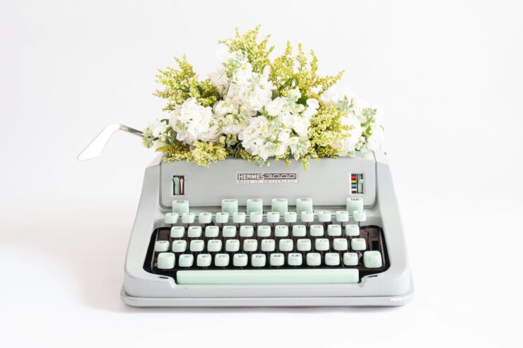 Photograph of a light grey typewriter with a floral arrangement in the paper bail