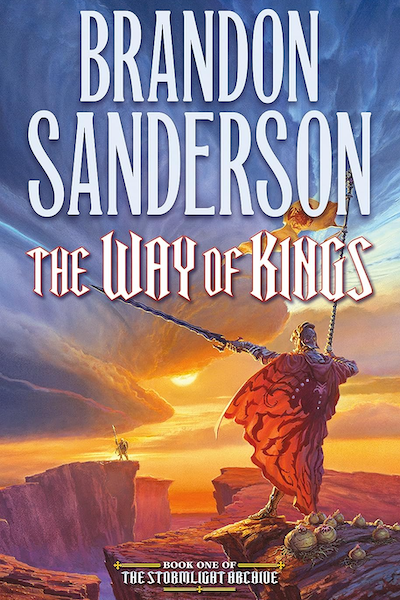 Cover of The Way of Kings by Brandon Sanderson, showing a figure standing on the edge of a ravine, holding a staff with a pennant and a sword, facing another figure holding a staff on the edge of another ravine, all against a dramatic stormy sky.