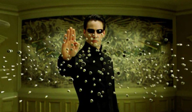 Neo (Keanu Reeves) holds up a hand to stop a hail of bullets in a scene from The Matrix