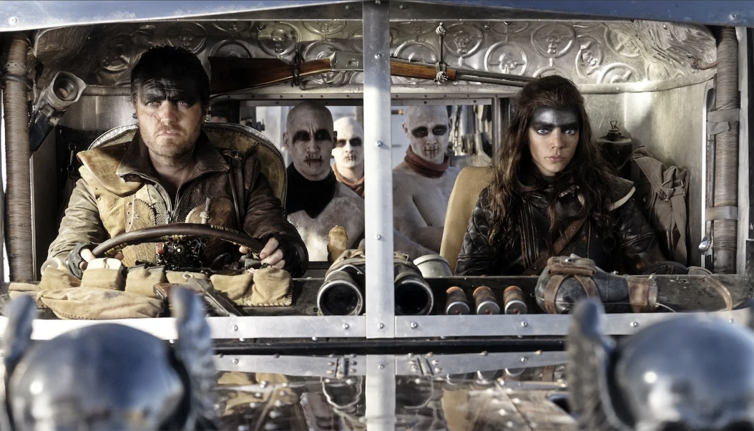 Praetorian Jack (Tom Burke) and Furiosa (Anya Taylor-Joy) in the cab of the War Rig, with three War Boys in the background