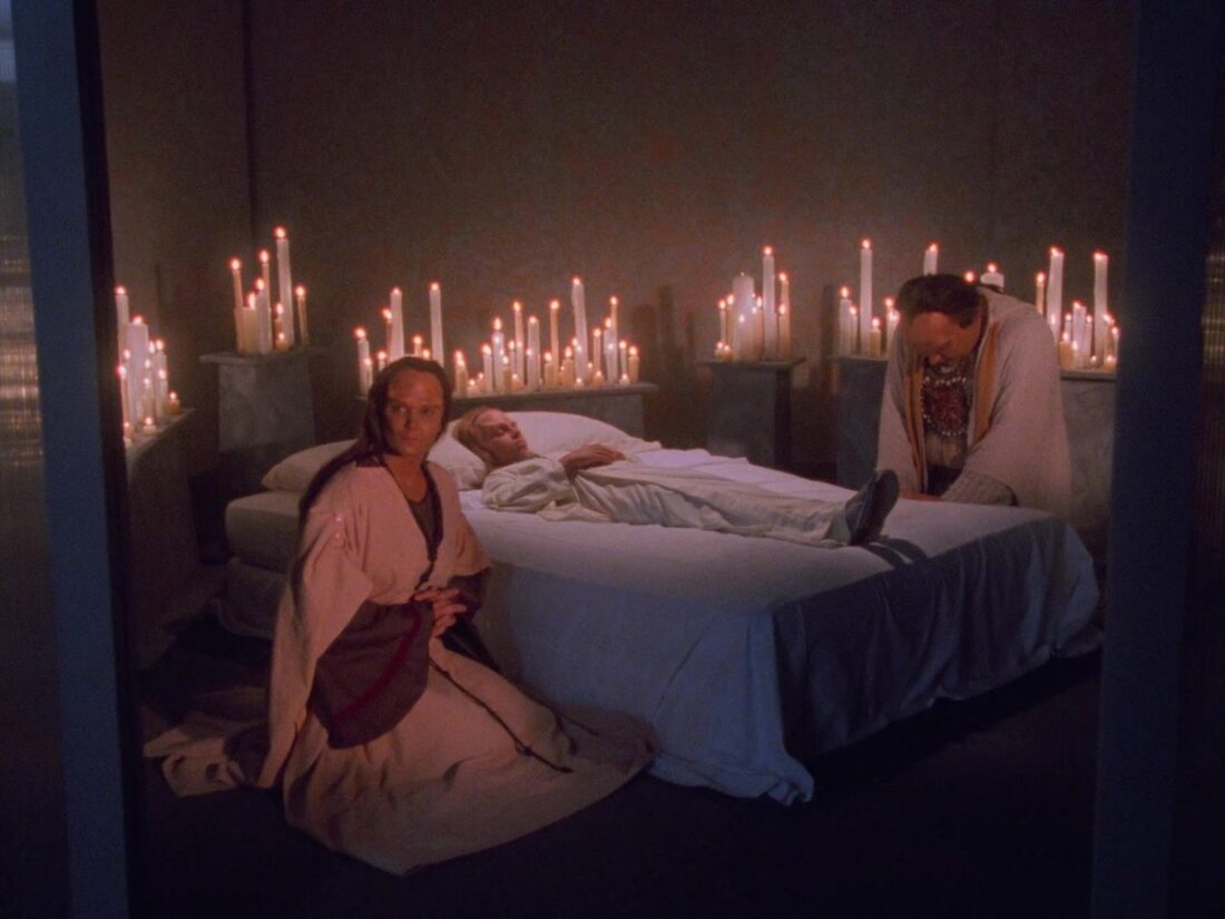 Two Onteen parents sit at their son's deathbed, surrounded by candles, in a scene from Babylon 5: Believers