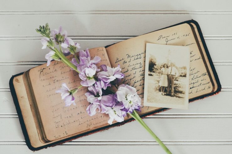Photo of an open diary, dated June 1925. A bunch of purple flowers and a sepia toned photograph of a man and woman are laid over the diary.