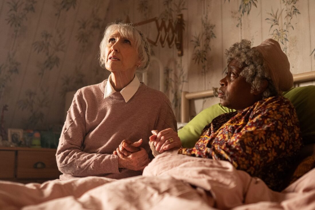 Mrs. Flood (Anita Dobson) and Cherry Sunday (Angela Wynter) sitting on Cherry's bed on Doctor Who, Empire of Death