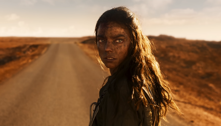 Furiosa (Anya Taylor-Joy) stands on a road in the middle of the Wasteland in a scene from Furiosa: A Mad Max Saga