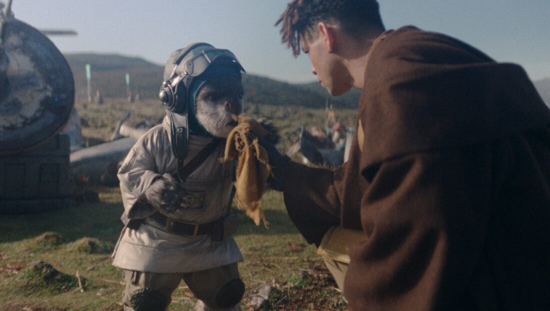 Bazil (Hassan Taj) and Yord Fandar (Charlie Barnett) in Lucasfilm's THE ACOLYTE, season one, Yord giving Bazil cloth to smell for tracking