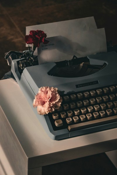 typewriter in shadow, with two flowers placed on the keys and in the carriage return