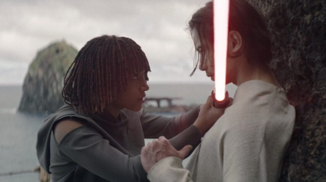 Amandla Stenberg as Osha, holding a lightsaber to Qimir's (Manny Jacinto) throat in The Acolyte, "Teach/Corrupt"