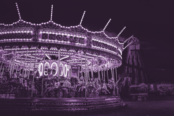 Black and white photo of a carousel and carnival booths lit up at night