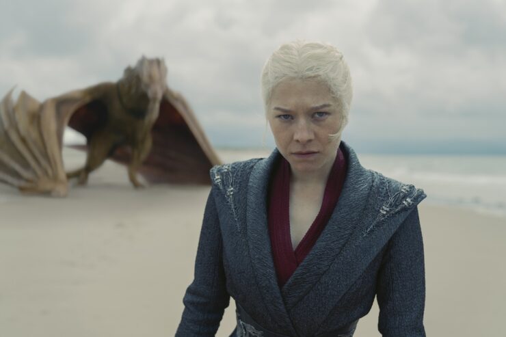 A scene from House of the Dragon, season 2 episode 7: Rhaenyra (Emma D'Arcy) stands on a beach, her dragon Syrax appears behind her