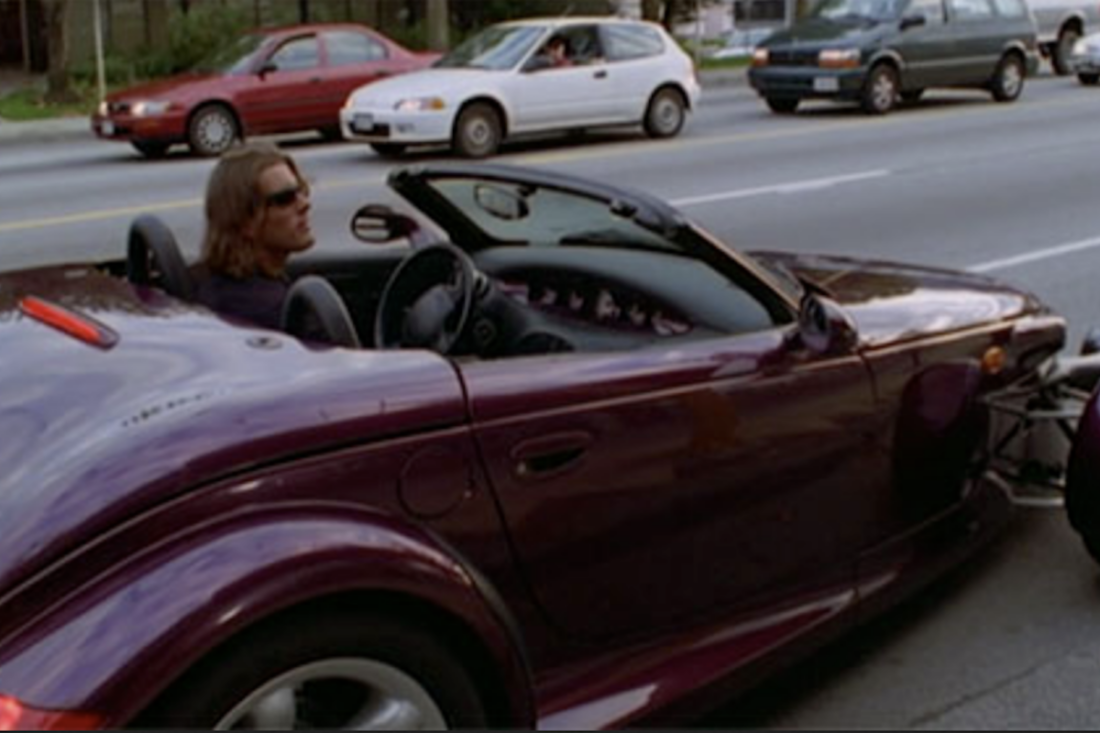 Johnny Domino (Matt McColm) in the driver's seat of a purple Plymouth Prowler in a scene from Night Man