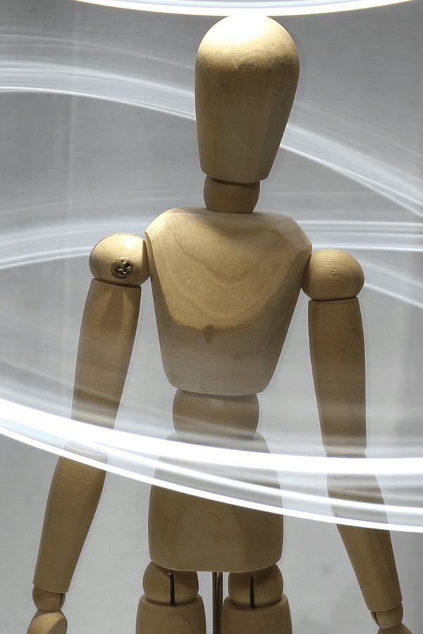 Photo of a wooden artist's mannequin surrounded by trails of light