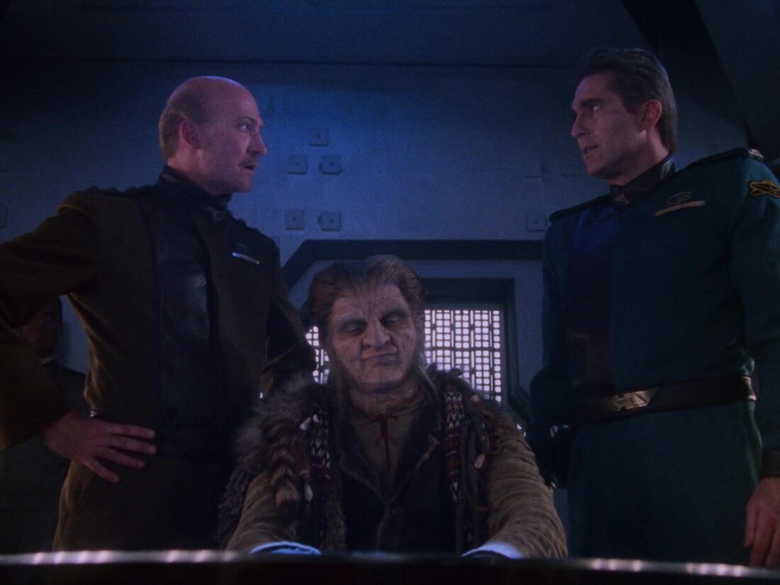 A scene from Babylon 5 "Babylon Squared": Major Krantz and Sinclair stand above Zathras