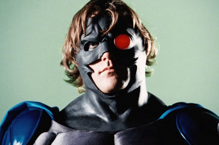 Close-up of Night Man in his superhero costume, featuring a black rubber cowl with one red eyepiece