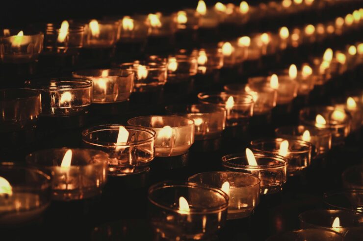 Shallow focus rows of lit teacandles in glass candle holders