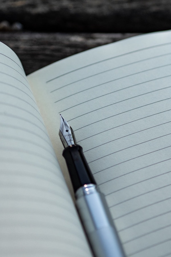 Photo of an open notebook with an uncapped pen