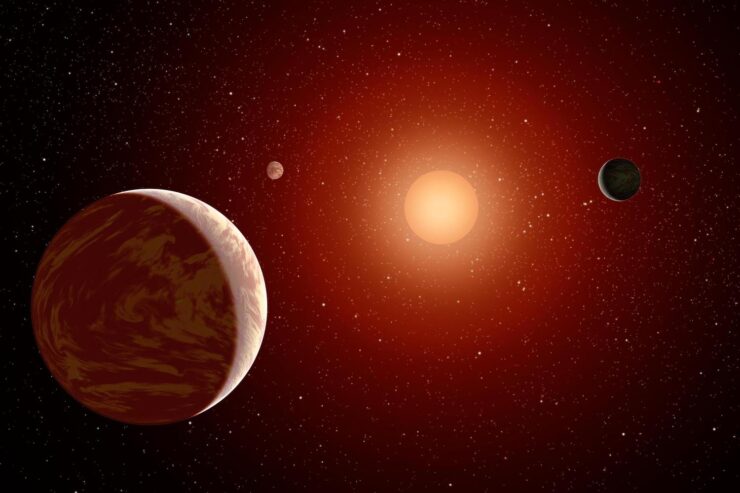 An artist's rendering of a red dwarf or M star, with three exoplanets orbiting.