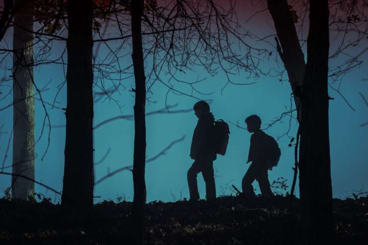 Two children are silhouetted against creepy blue light in the woods in Salem's Lot