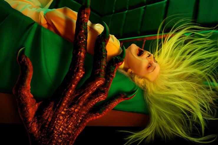 Cropped poster for American Horror Stories showing a woman lying down getting grabbed by monstrous hand.