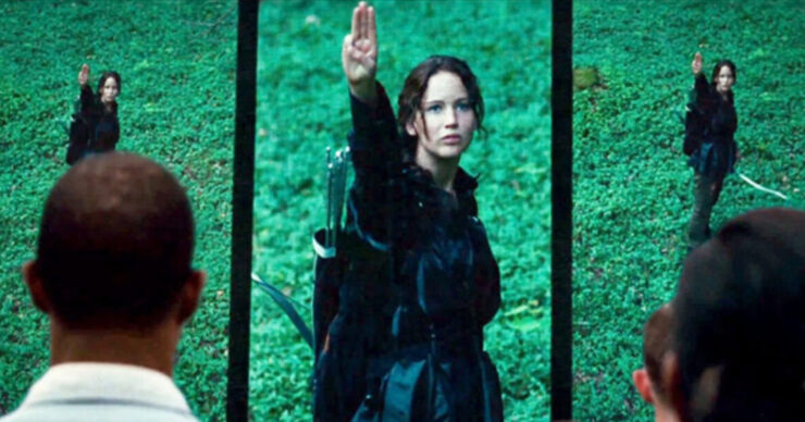 Katniss Everdeen (Jennifer Lawrence) holds up a three-fingered salute in The Hunger Games