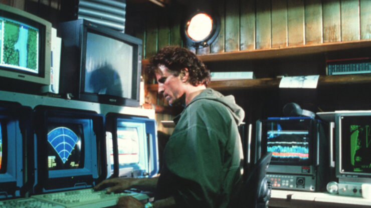 Dr. Jonathan Dempsey (Ted Danson) sits at an array of computers and sonar displays in Loch Ness (1996)