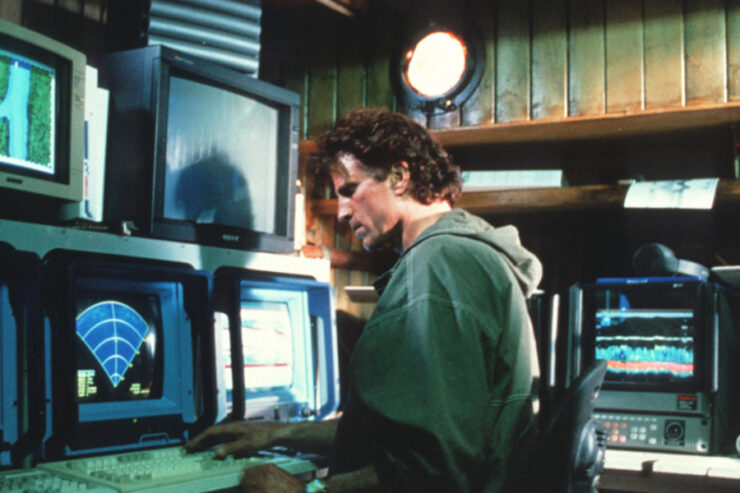 Dr. Jonathan Dempsey (Ted Danson) sits at an array of computers and sonar displays in Loch Ness (1996)