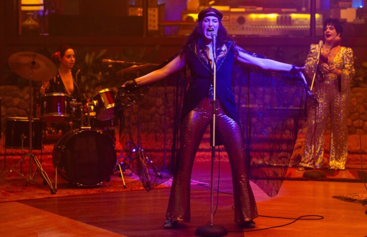 (L-R) Rio Vidal (Aubrey Plaza), Agatha Harkness (Kathryn Hahn) and Lilia Calderu (Patti LuPone) playing in a band, Agatha singing with arms thrown wide in Agatha All Along, "If I Can't Reach You / Let My Song Teach You"