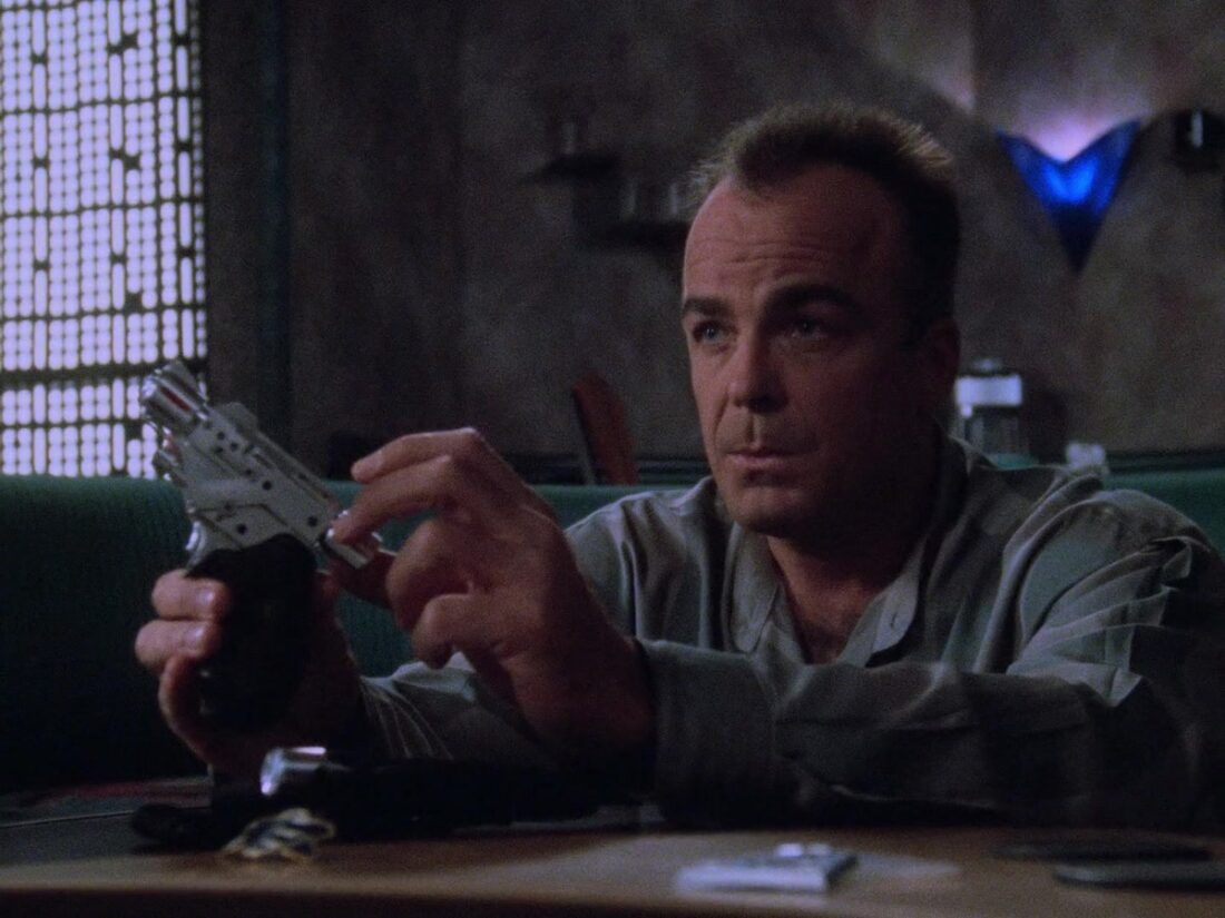 Garibaldi is sitting in his quarters while holding a gun in a scene from Babylon 5, "The Geometry of Shadows"