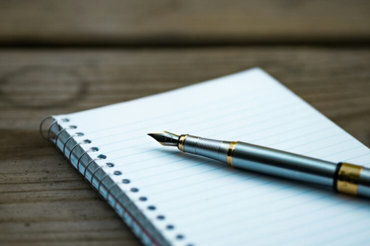 Photo of a fountain pen resting on a blank notepad