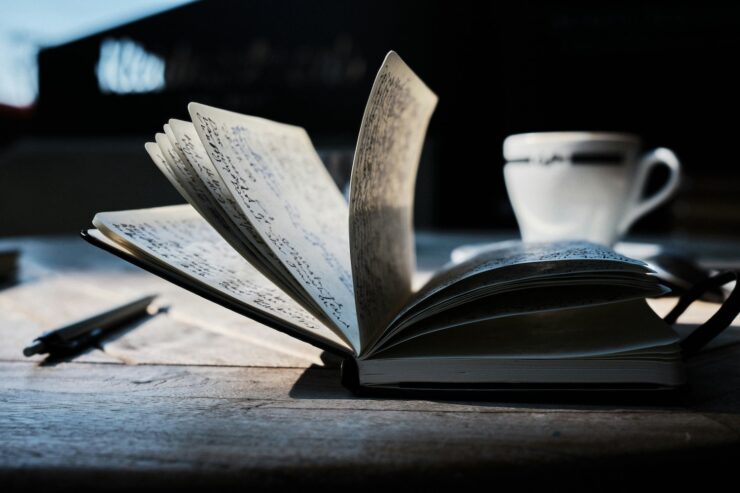 open notebook, pen, and coffee cup on a table