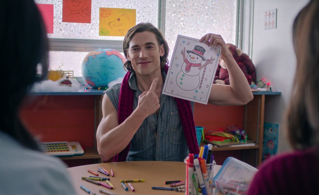 Dustin Milligan as Jack Snowman in Hot Frosty holding up a child's drawing of a snowman and grinning