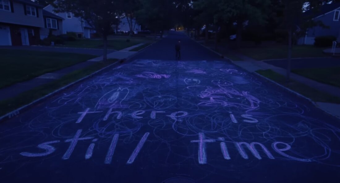 The message: "There is still time" appears, written in chalk on a suburban street in I Saw The TV Glow, for anyone who might need that.