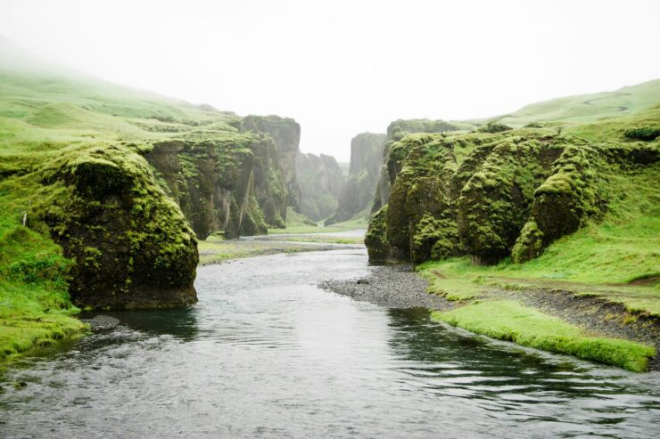 Photo of a river in Iceland, bordered by grassy shores and cliffs