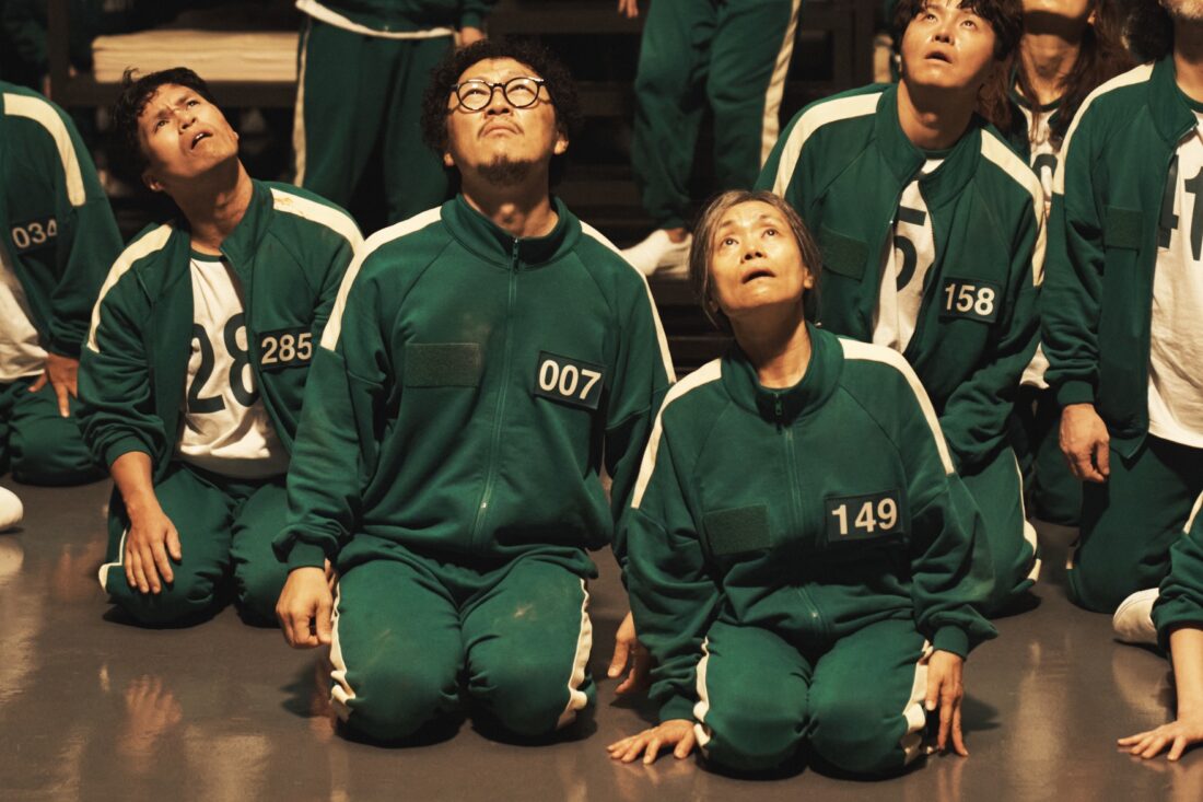 Squid Game S2 (L to R) Yang Dong-geun as Park Yong-sik, Kang Ae-sim as Jang Geum-ja in Squid Game S2 looking up into light