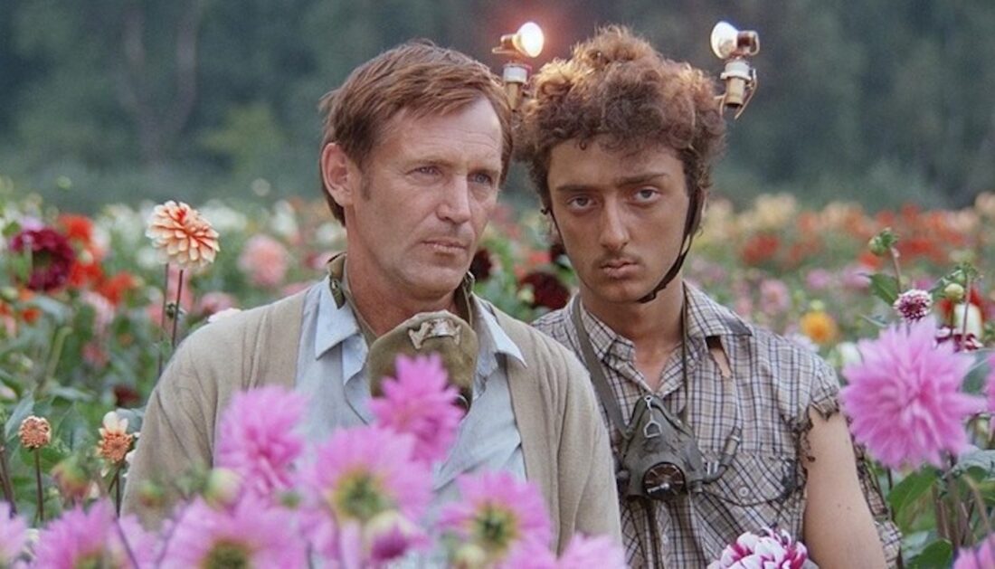 Uncle Vova (Stanislav Lyubshin) and Gedevan (Levan Gabriadze) stand in a field of flowers in a scene from Kin-dza-dza!