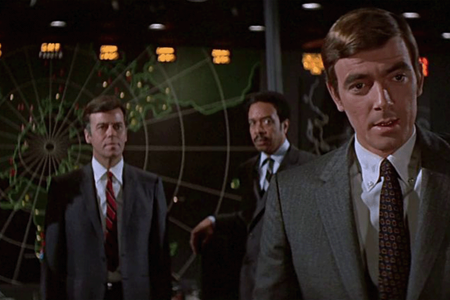 Three men stand in front of a large global map; Image from Colossus: The Forbin Project