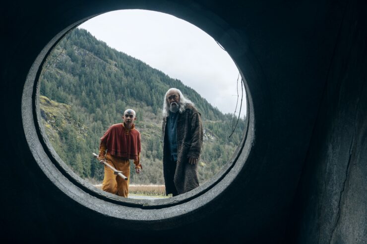 Avatar: The Last Airbender. (L to R) Gordon Cormier as Aang, Paul Sun-Hyung Lee as Iroh, both of them looking through a circular opening left by Avatar Kyoshi into the prison below Ba Sing Se in season 2 of Avatar: The Last Airbender