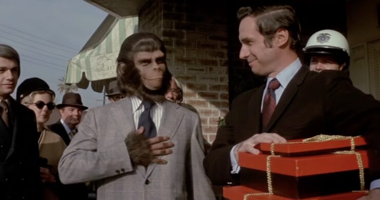 Dr. Cornelius in a human suit, hand over heart while humans smile around him in Escape From the Planet of the Apes