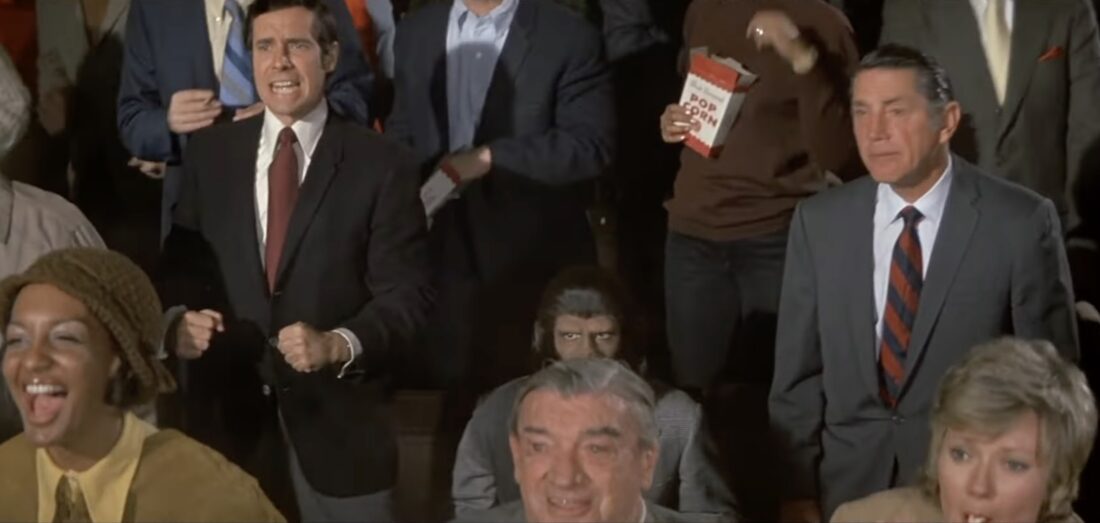 Dr. Cornelius sitting and affronted while humans cheer a boxing match in Escape From the Planet of the Apes