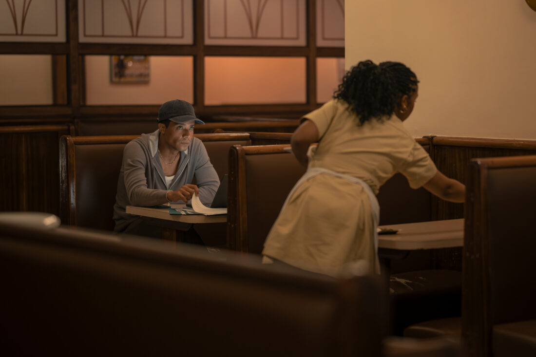 Jacob Anderson as Louis De Pointe Du Lac and Delainey Hayles as Regina, her bussing tables while Louis watches from a booth in The Vampire Lestat, episode 4