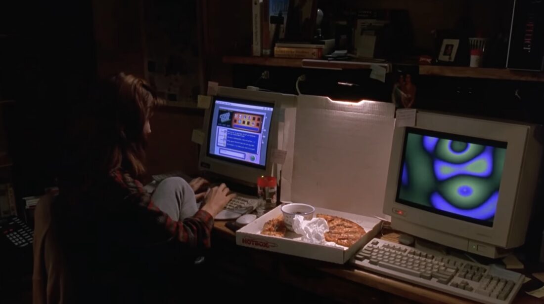 Sandra Bullock sitting in front of two '90s PCs with pizza and candy in The Net